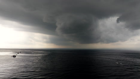 dramatic stormy cumulus clouds with boat navigating over dark sea