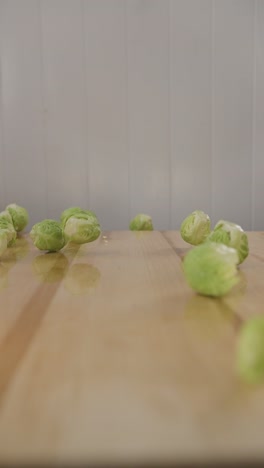 macro food close up brussels sprouts falling on to wooden table , organic green vegetable diet