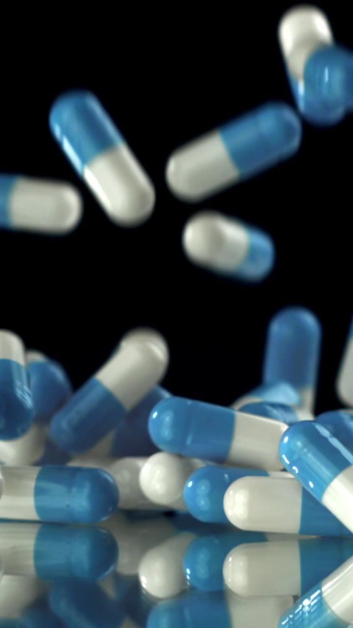 Blue and White Medical Capsules Falling in Slow Motion