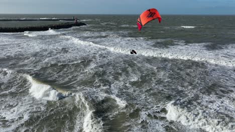 kiteboarder showing his skills jumping in stormy sea with waves