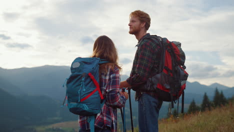 two backpackers look sunrise mountains landscape. hiking couple relax outside.