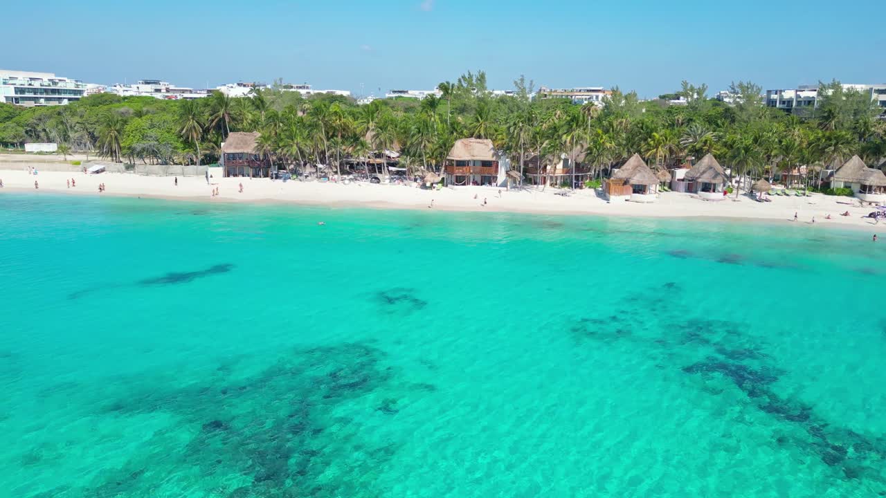 Tranquil tropical beach with palm trees, clear water and huts in Playa del Carmen