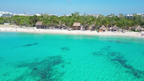 tranquil tropical beach with palm trees, clear water and huts in playa del carmen