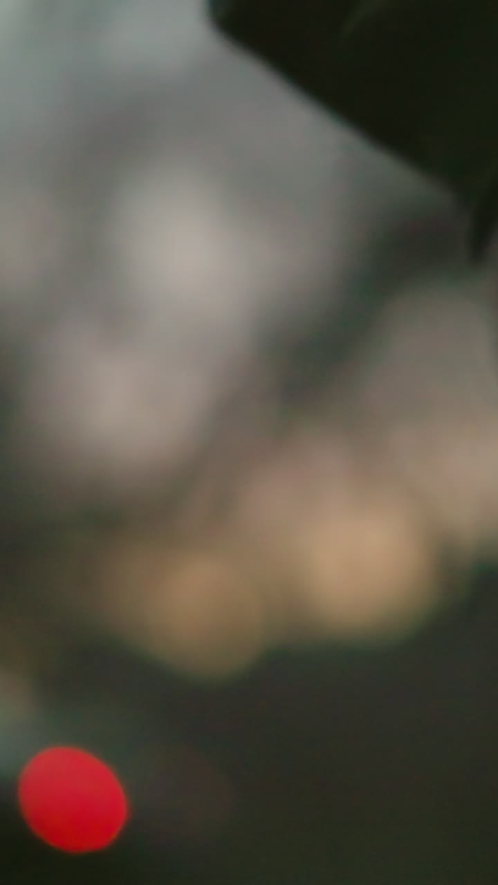 불타는 담배를 들고 있는 남자의 손의 근접한 모습, 반이는 끝이 흐릿한 배경에 생생한 은 점을 만니다.