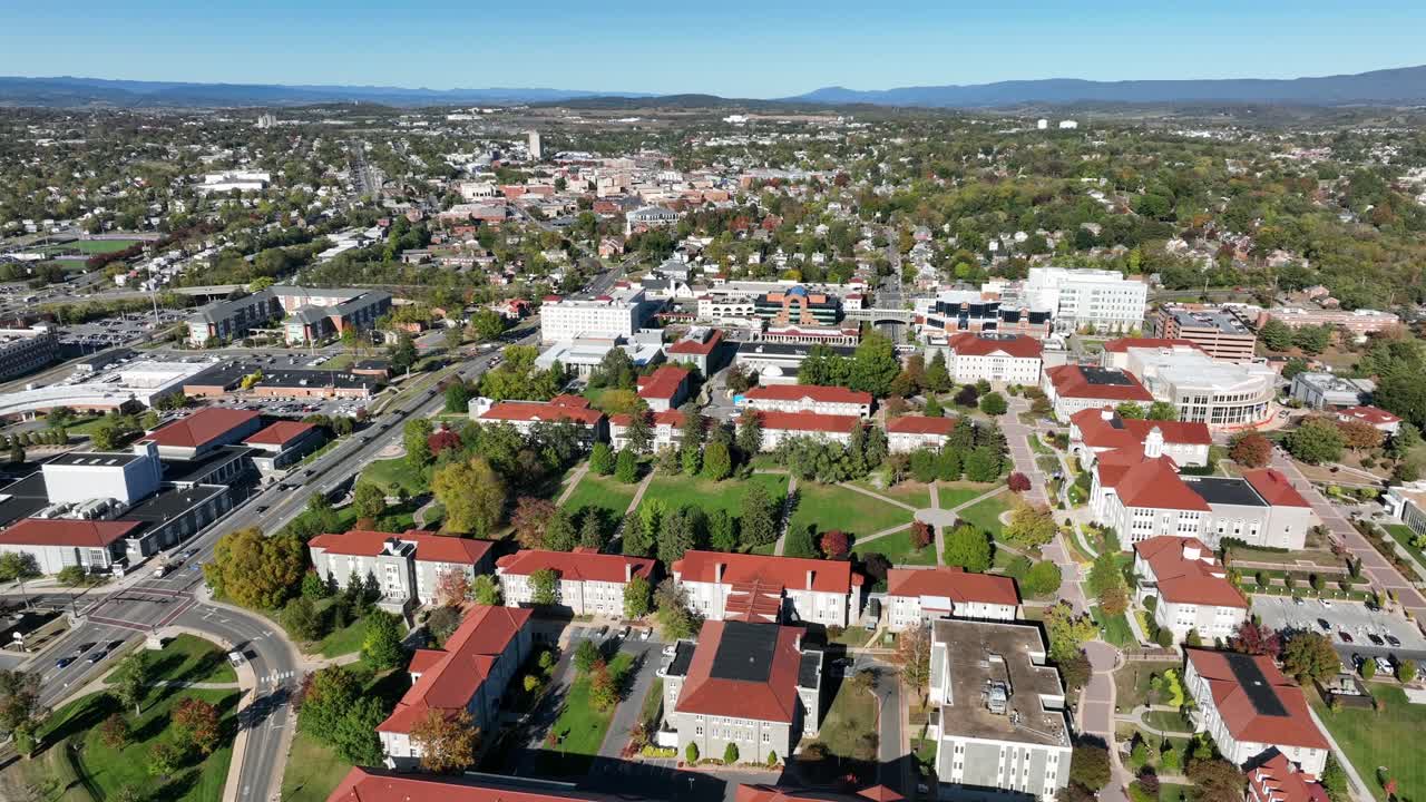 James Madison university buildings campus in Harrisonburg, Virginia. Descend wide shot. Sunny day with blue sky in fall. Traffic on straight Main Street