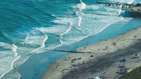 una foto aérea de las olas azules y blancas que se estrellan en la playa de arena marrón de atlantic city, nj