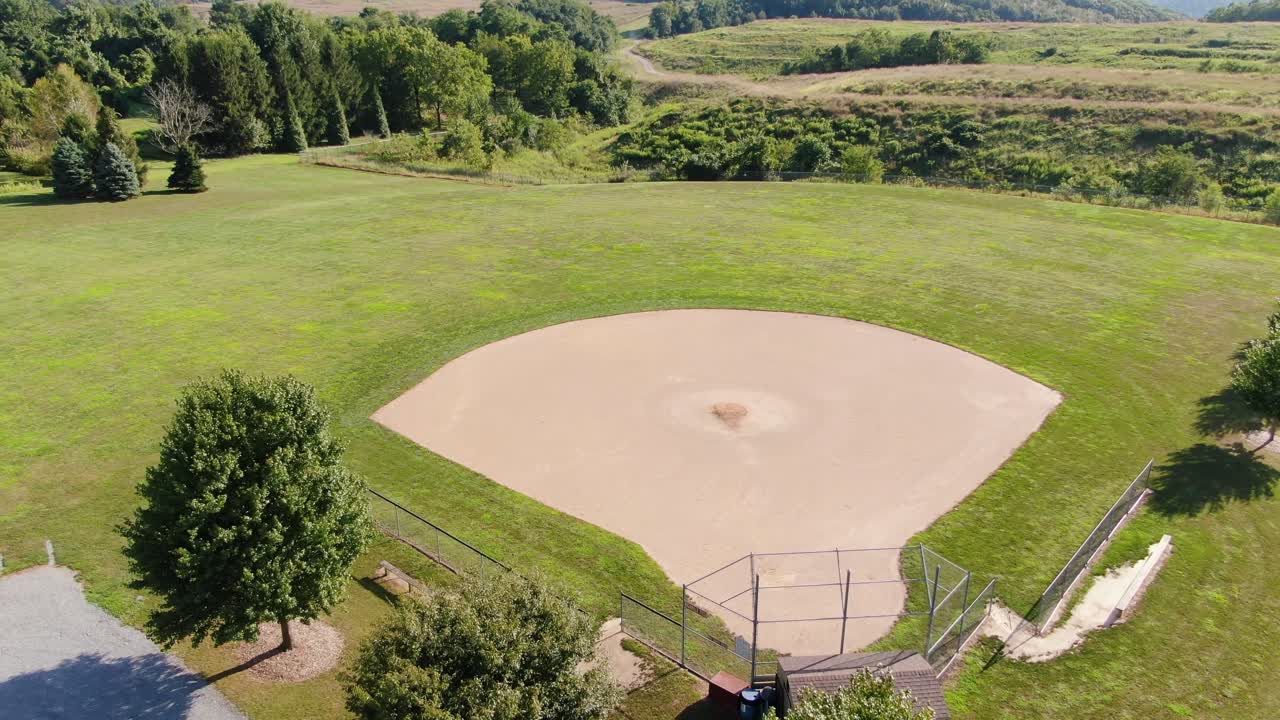 시골 시골, 멀리 있는 나무와 들판에 있는 야구 다이아몬드의 상승하는 공중