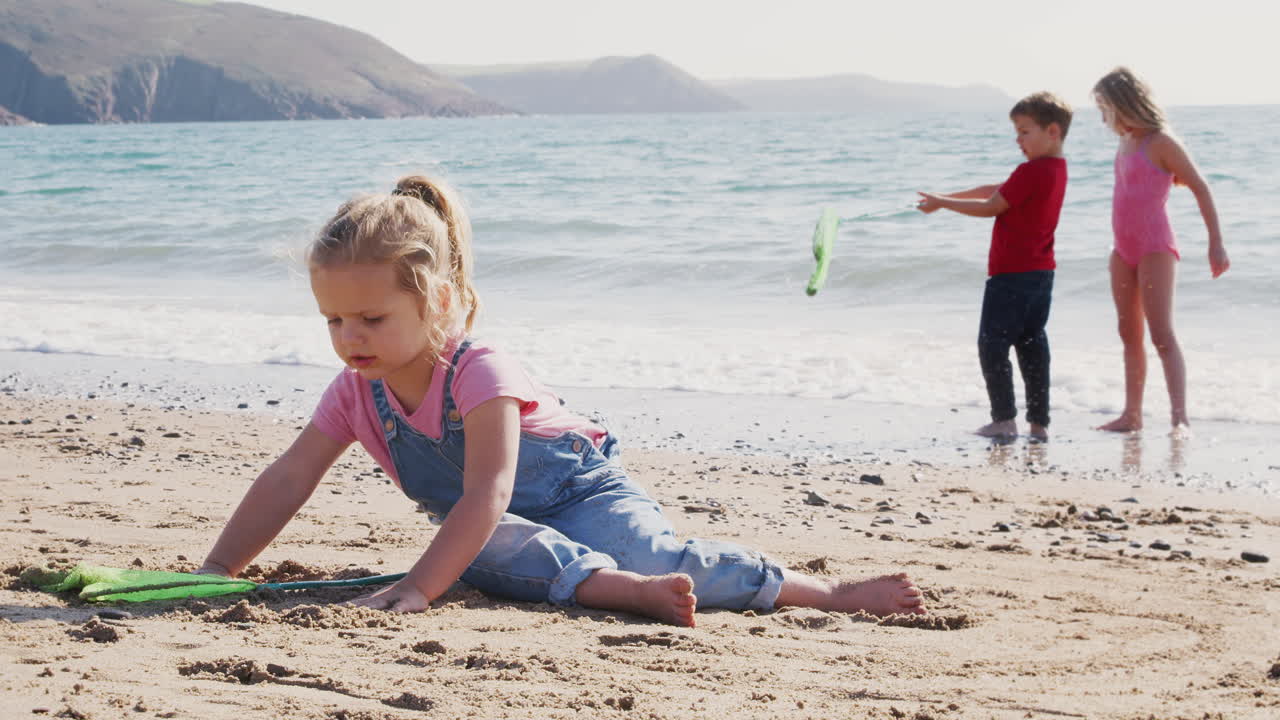 niños divirtiéndose en la playa cavando en la arena y explorando con la red de pesca