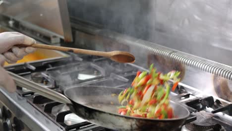 chef cocinando y flambeando verduras en una sartén, imágenes de 4k