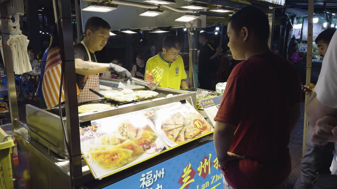 Man Cooks for Customer Waiting on Jalan Alor Food Street. Kuala Lumpur, Malaysia. Slow Motion