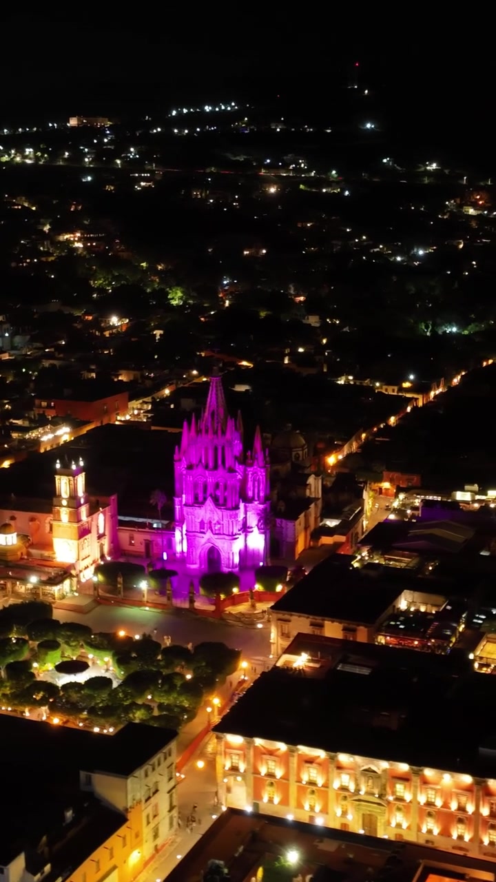 Centro storico di San Miguel de Allende di notte, Messico. Orbita aerea verticale attorno alla Parroquia de San Miguel Arcángel illuminata e alla piazza principale Jardín Allende