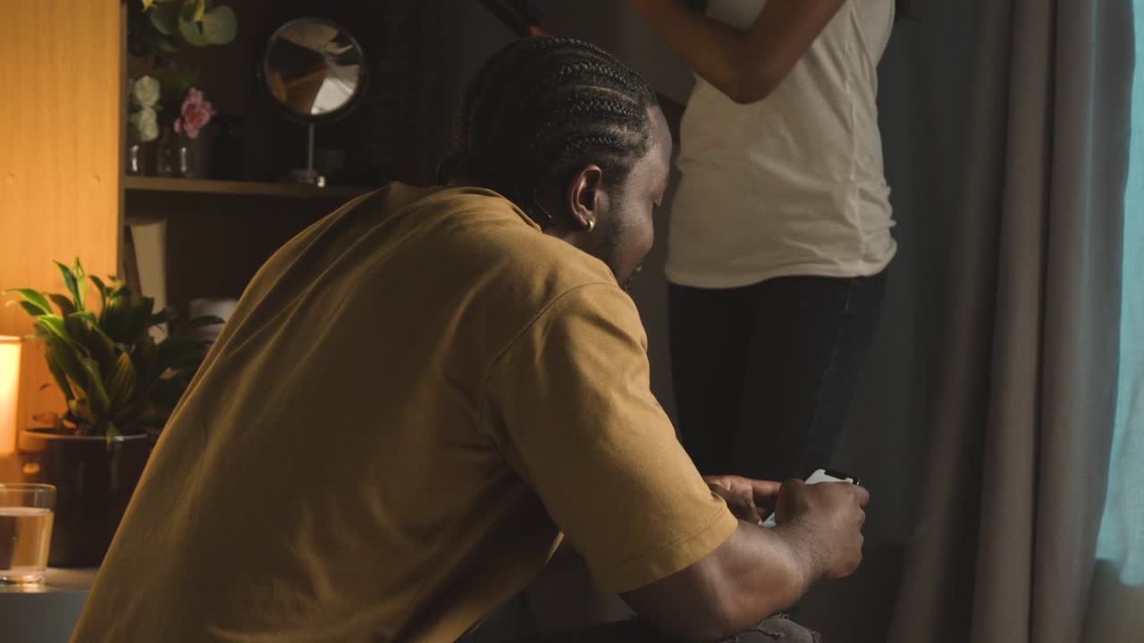 pareja joven relajándose en casa por la noche con un hombre navegando por internet en el teléfono móvil 1