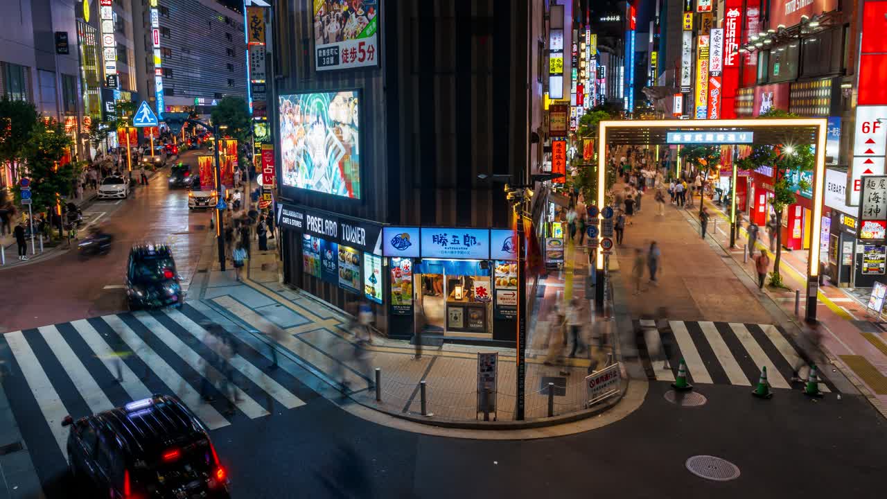 Busy street intersection near Shinjuku station, high angle, wide, night time lapse shot