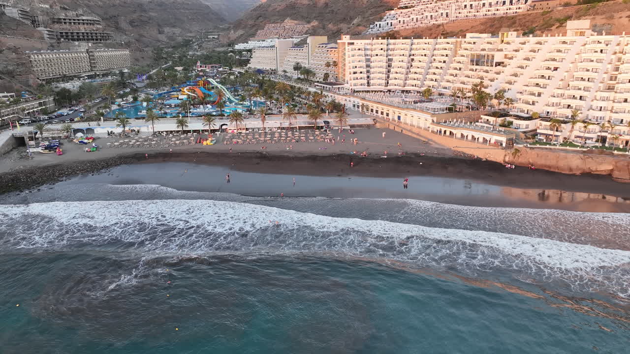 toma aerea en la distancia a la orilla de la playa taurito en mogan y donde se puede ver a la gente bañándose