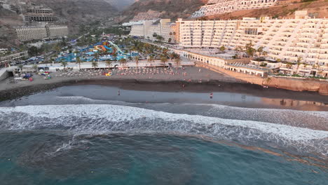 aerial shot in distance to the shore of the taurito beach in mogan and where people can be seen bathing