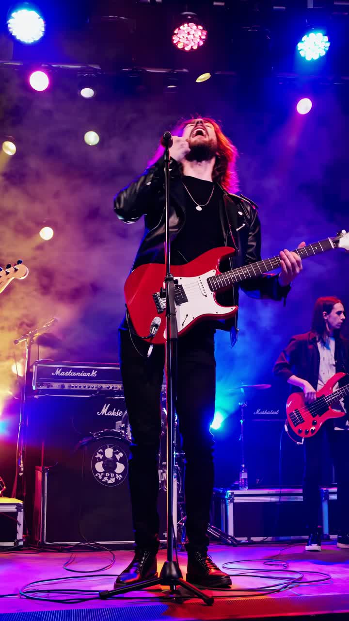 Inquadratura dinamica dal basso di una rock band che si esibisce dal vivo sul palco, luci vivaci e nebbia