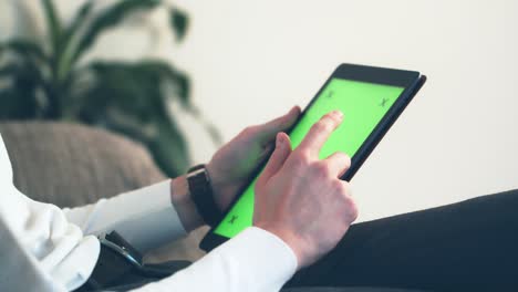 Man-sitting-on-couch-using-tablet-with-chroma-key-green-screen