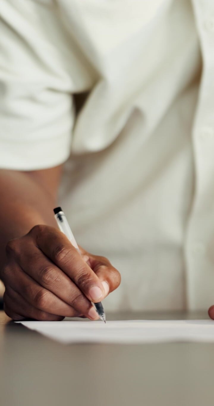 Persona che scrive su carta con una penna