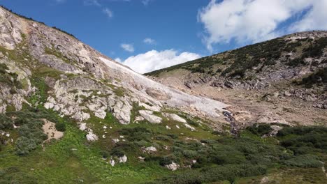 volando hacia la plataforma de nieve perenne con cascada en las montañas de colorado, antena