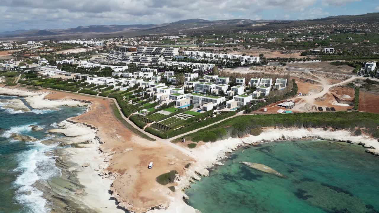 A cinematic drone showcases a row of white homes, each with its own outdoor swimming pool, forming a serene and elegant coastal neighborhood.