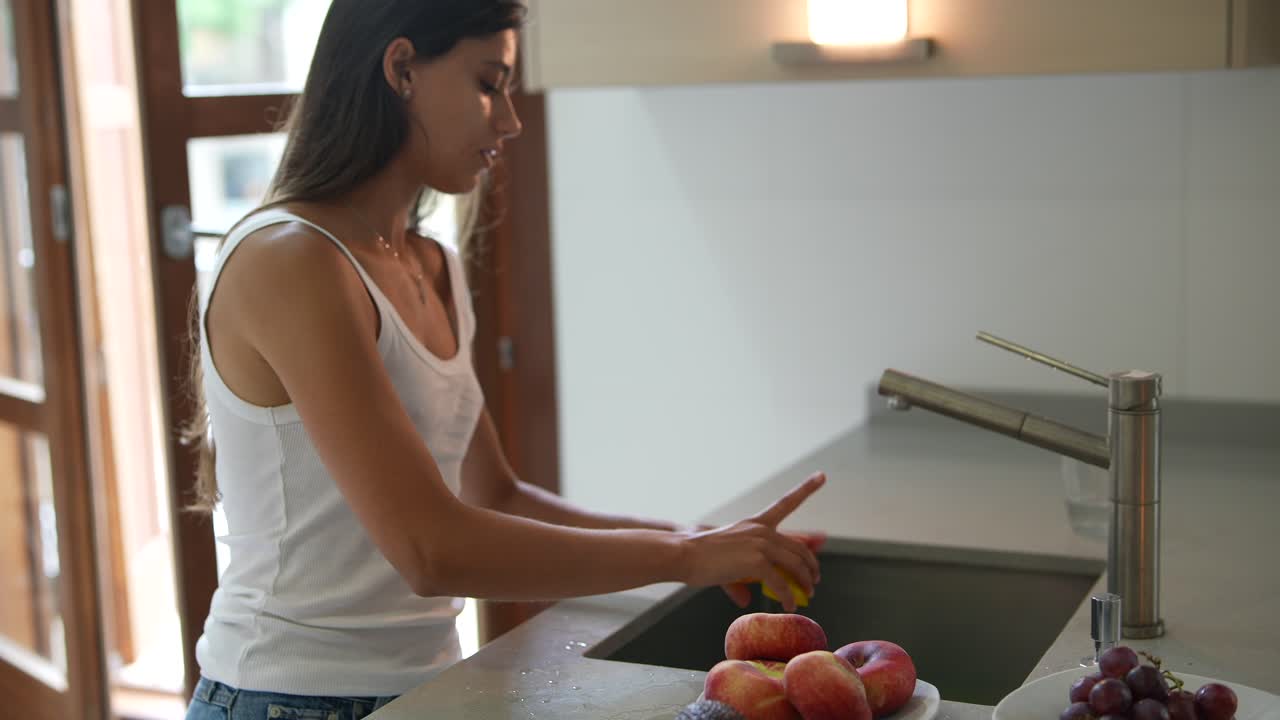 mujer lavando frutas y verduras en la cocina