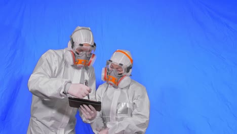 scientist virologist in respirator makes write in an tablet computer with stylus. man and woman wearing protective medical mask. chroma key blue.