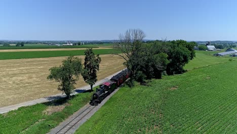 a steam train chugs along the tracks, surrounded by vibrant green fields and tall trees under a bright blue sky