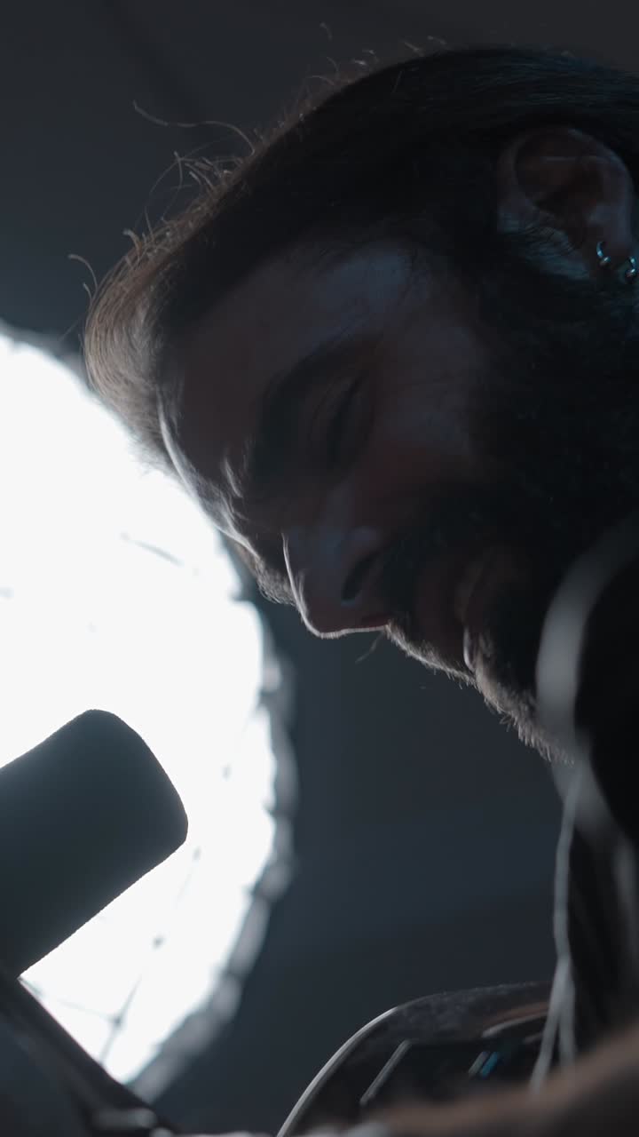 Bearded man singing into a microphone in a studio