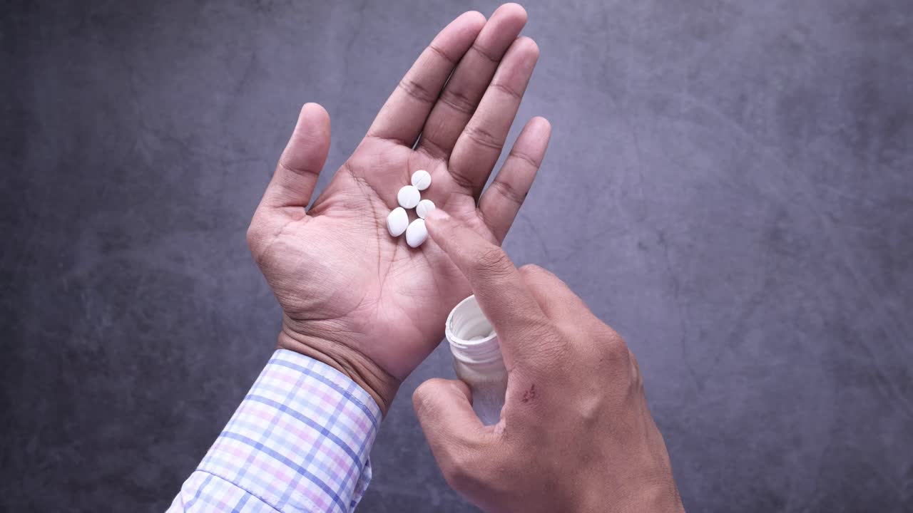 Person taking pills from a bottle