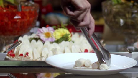 Close-up-of-a-person's-hand-serving-gourmet-vegetables-on-a-plate-from-a-colorful-platter