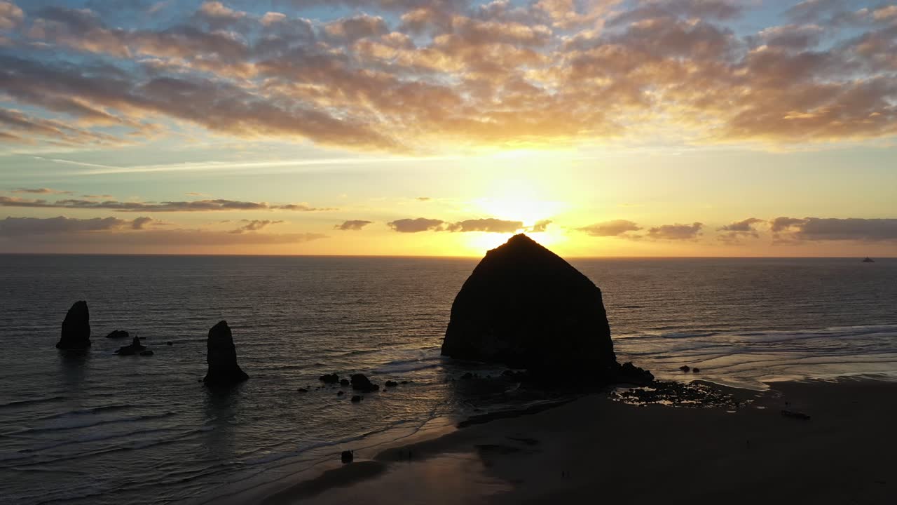 Majestic static aerial sunset view of sea stacks and boulder in ocean on the beach of California.