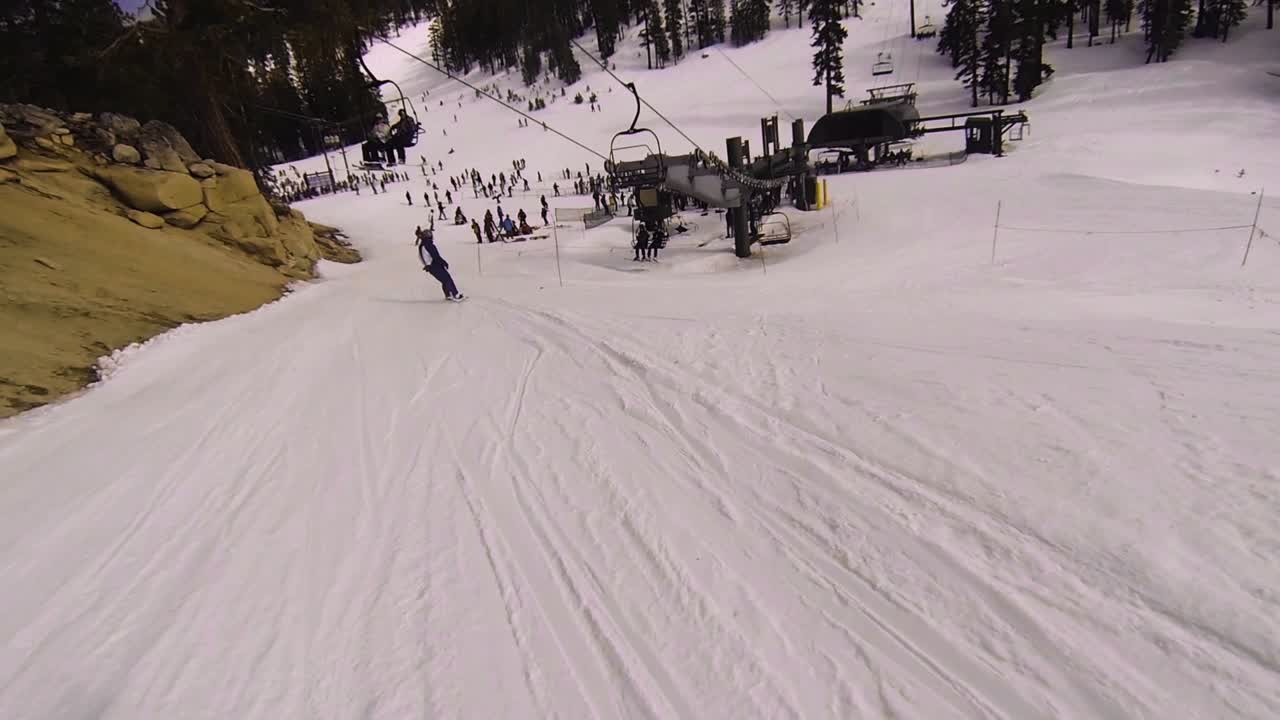 POV zig-zag chasing behind a snowboarder down the slope toward the lift line.