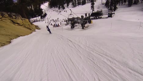 pov zig-zag chasing behind a snowboarder down the slope toward the lift line.
