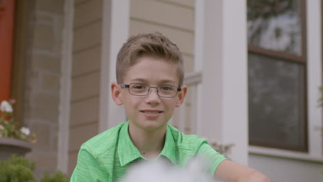 Cute-little-boy-in-front-yard-of-house-smiles-at-camera