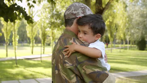 happy military dad holding son in arms outdoors