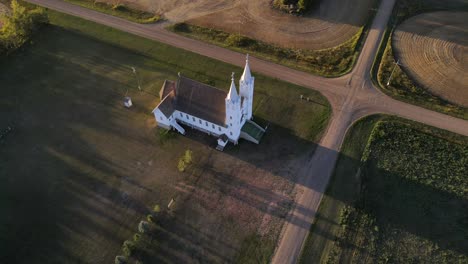 Aerial-shot-of-roman-catholic-church-in-north-American-prairie-during-sunset