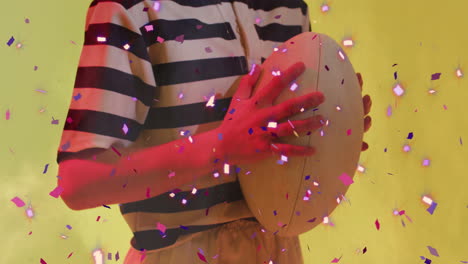 animation of confetti falling over caucasian female rugby player holding ball