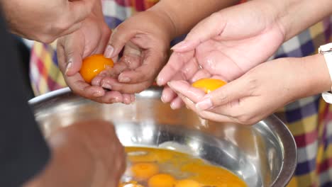 close up of hands separate egg yolks from egg whites in thai dessert recipes.