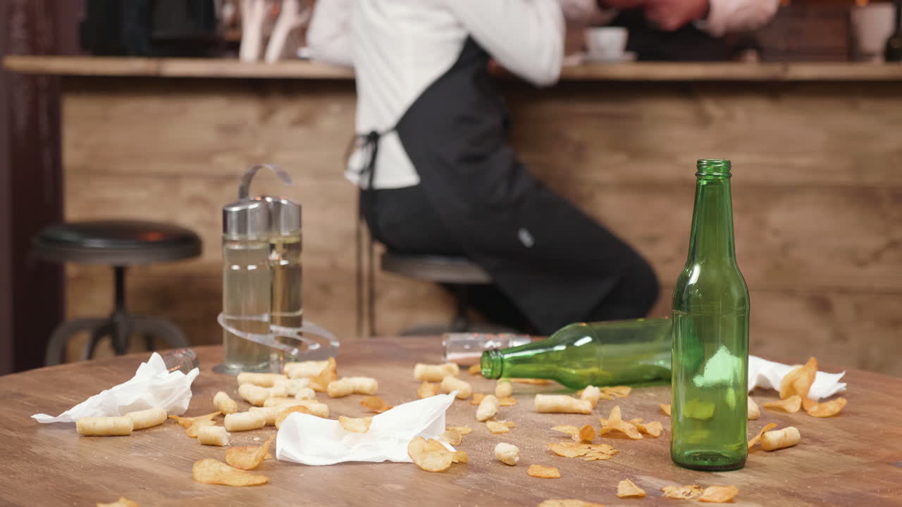 Messy Bar Table with Empty Beer Bottles and Chips