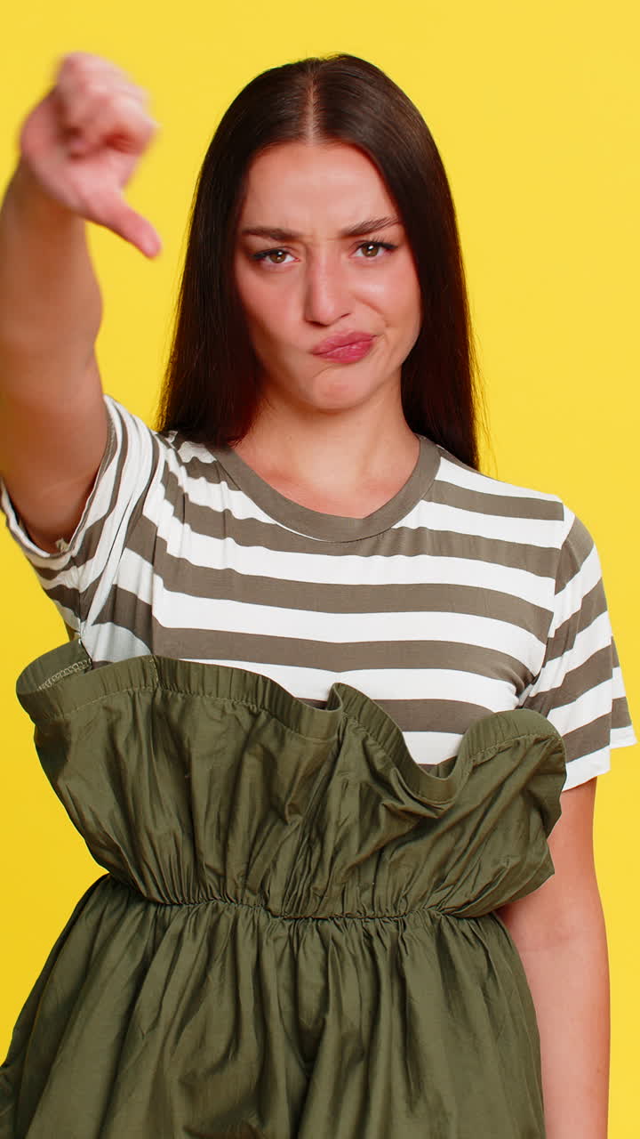 Woman showing thumbs down serious disappointed face expressing dislike rejection negative emotion