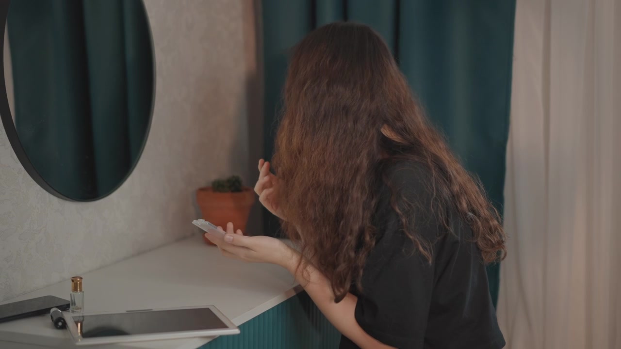 Mujer inclinada sobre el lavabo del baño con las manos ahuecadas cerca del grifo cromado, enjuagándose la cara en un baño moderno y tranquilo con tocador verde azulado, luz suave, espejo y un interior de hogar ordenado, con mujer, lavándose.