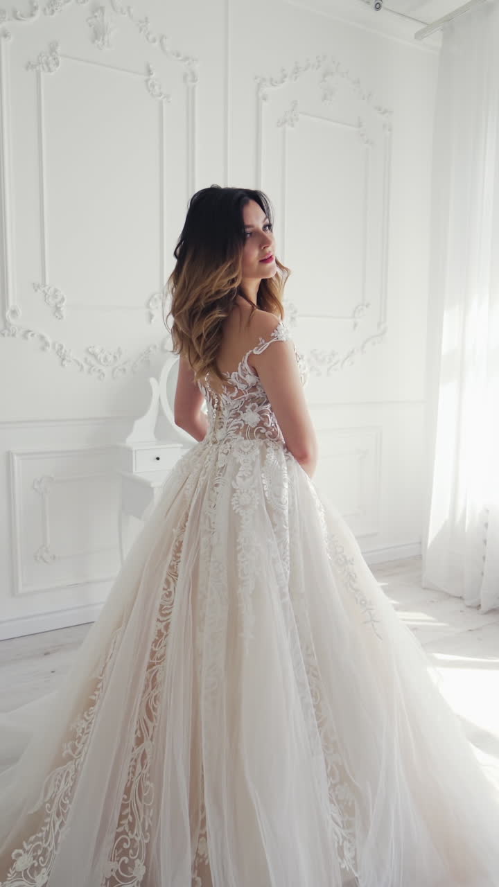 Luxury bride in dress. Portrait of the beautiful bride against a window indoors Vertical video