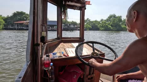 man steering a wooden boat on a sunny day