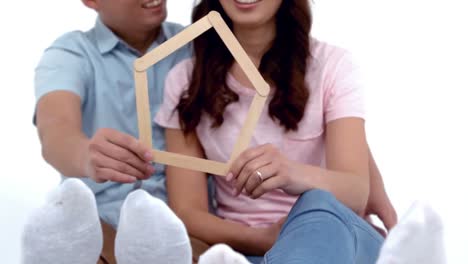 una joven pareja feliz con forma de casa