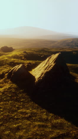 beautiful sunset over a grassy field with rocks and mountains in the distance