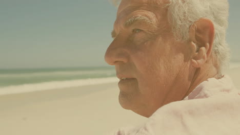 gazing thoughtfully at ocean, elderly man with white hair on beach