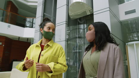 Multiethnic-Female-Colleagues-in-Masks-Walking-and-Speaking