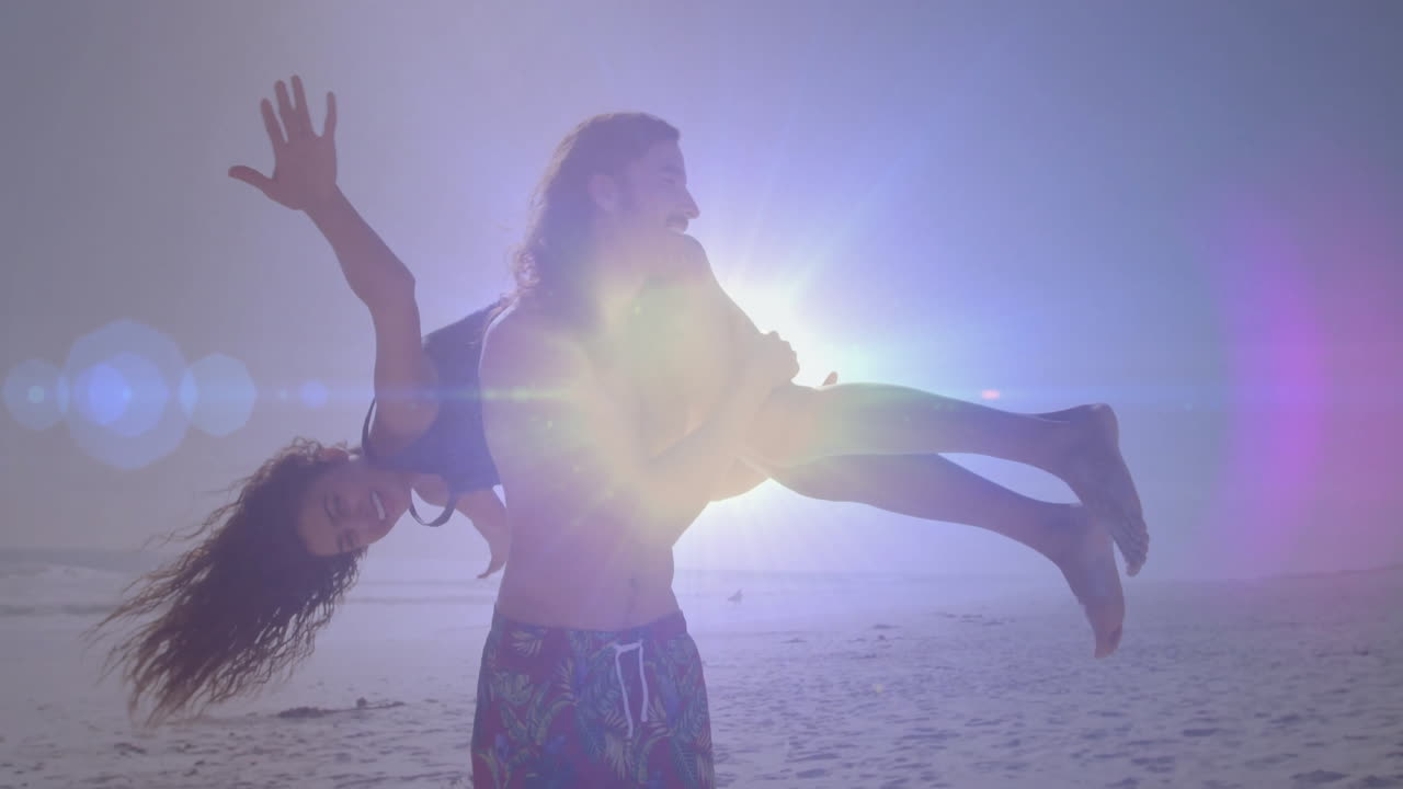 Carrying woman playfully, man enjoying beach with bright sunlight in background