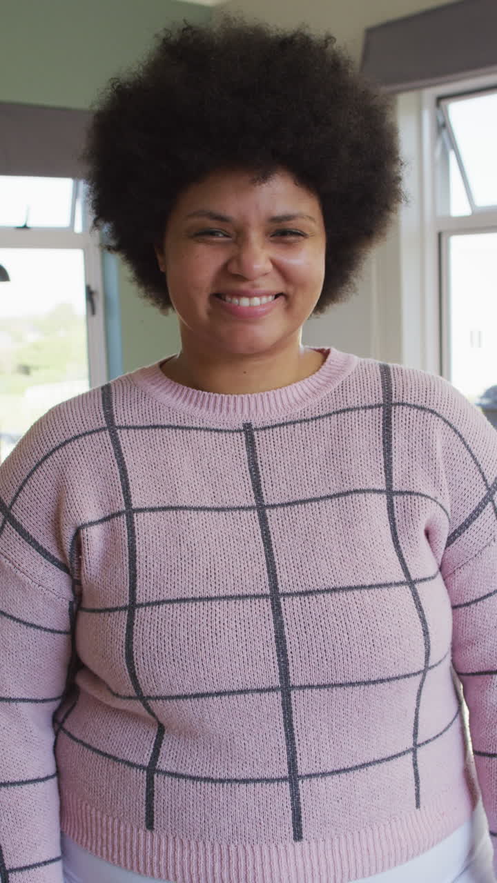 video vertical del retrato de una mujer biracial feliz en la sala de estar