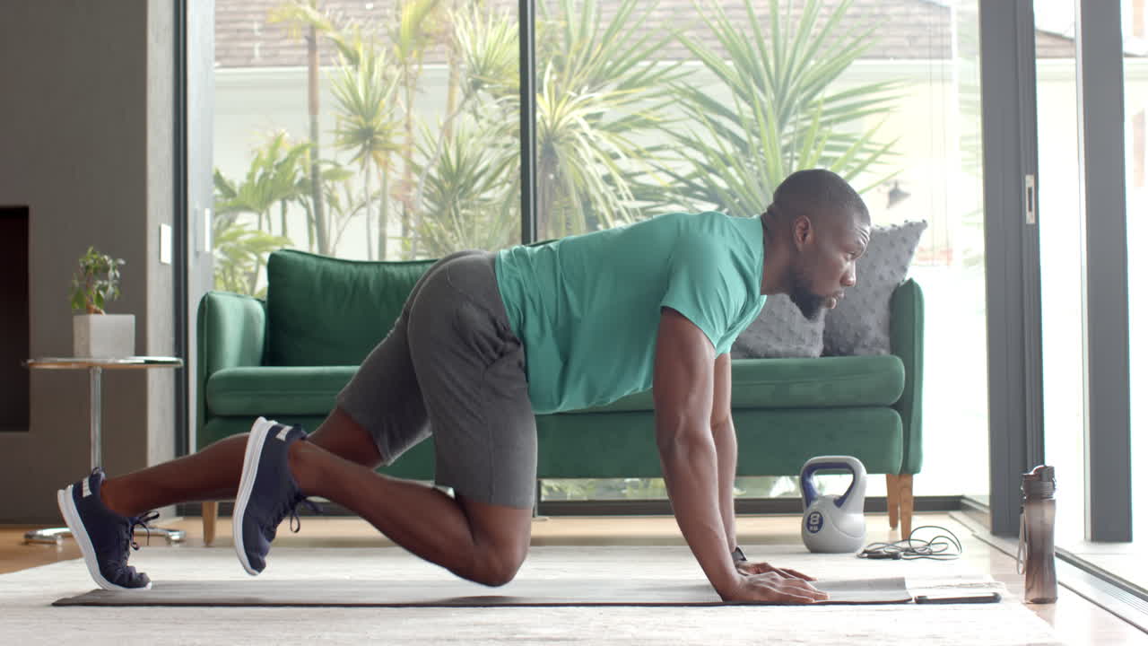 Strong and fit man doing push-ups on yoga mat with kettlebell nearby